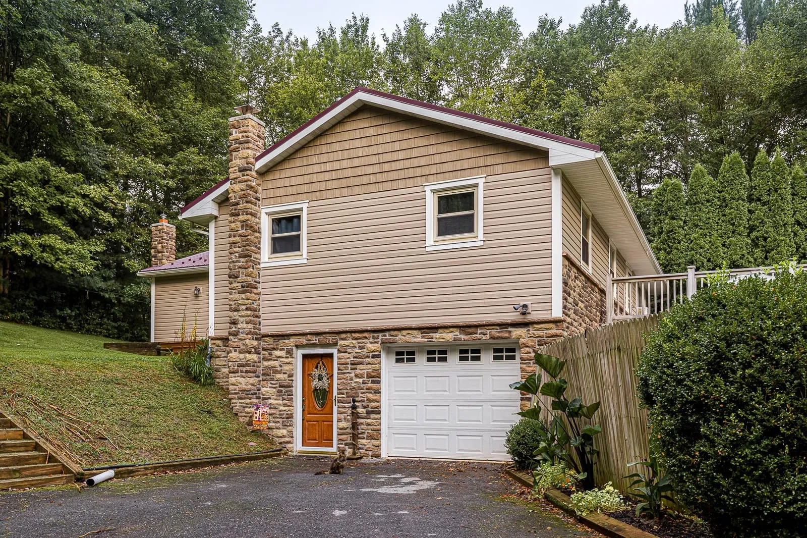 A two-storey home re-sided by Esh Builders in tan lap siding, with a shake accent in the gable and stone below