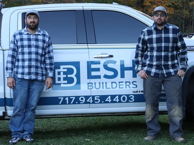 Matthew and Michael Esh, twin brothers and third-generation owners of Esh Builders, in front of an Esh Builders truck